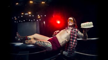 Porträtt på Eric Svenseth liggandes på repen av en wrestlingring med en tårta i handen - en replika på den han tårtade kungen med.