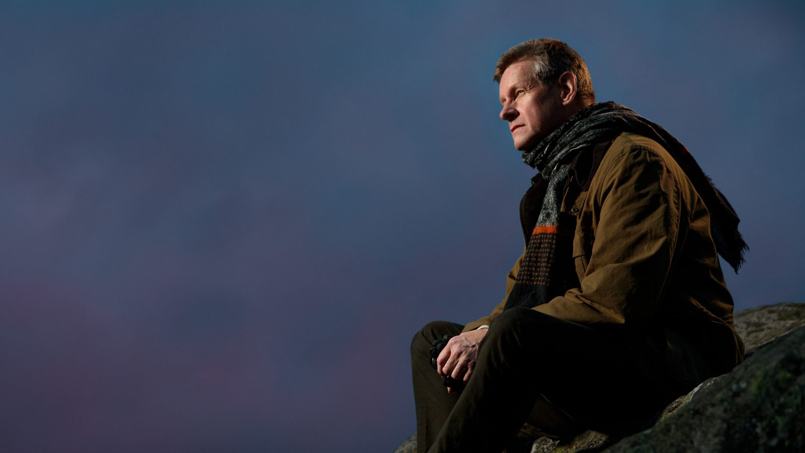 Robert Karjel, författare, sitter på en bergknalle och ser ut över staden.