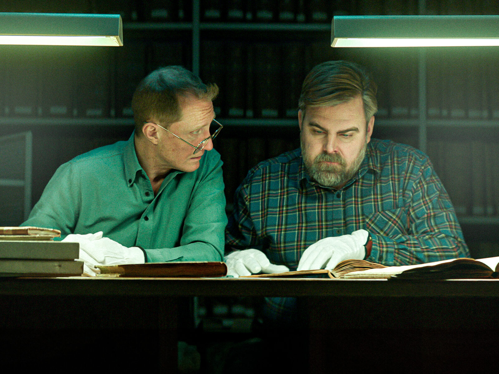 Filmscen ur Genombrottet, polisen John och släktforskaren Per är i ett arkiv.